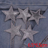 Five silver glitter star patches are displayed on a denim fabric background.