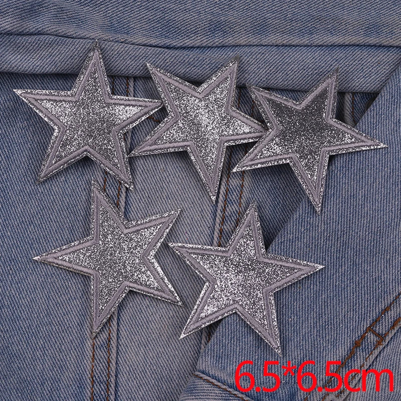 Five silver glitter star patches are displayed on a denim fabric background.