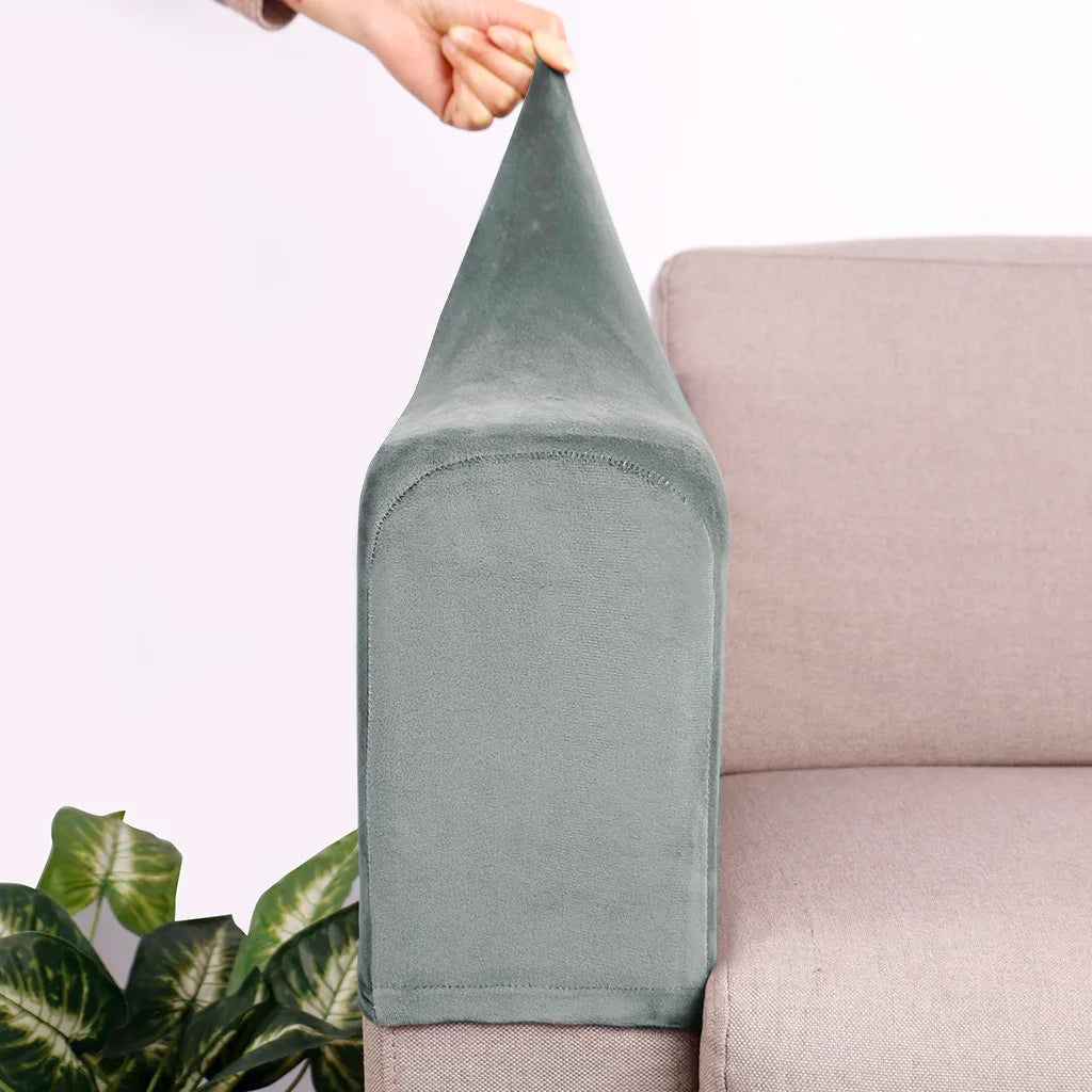 A close-up of a gray velvet sofa armrest cover being held by a hand, resting on a light pink sofa.