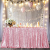 A pink sequin rectangle table cover draped with fairy lights and balloons for a party setting.