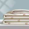 A stack of light beige embroidered cooling summer quilts with small horse designs.