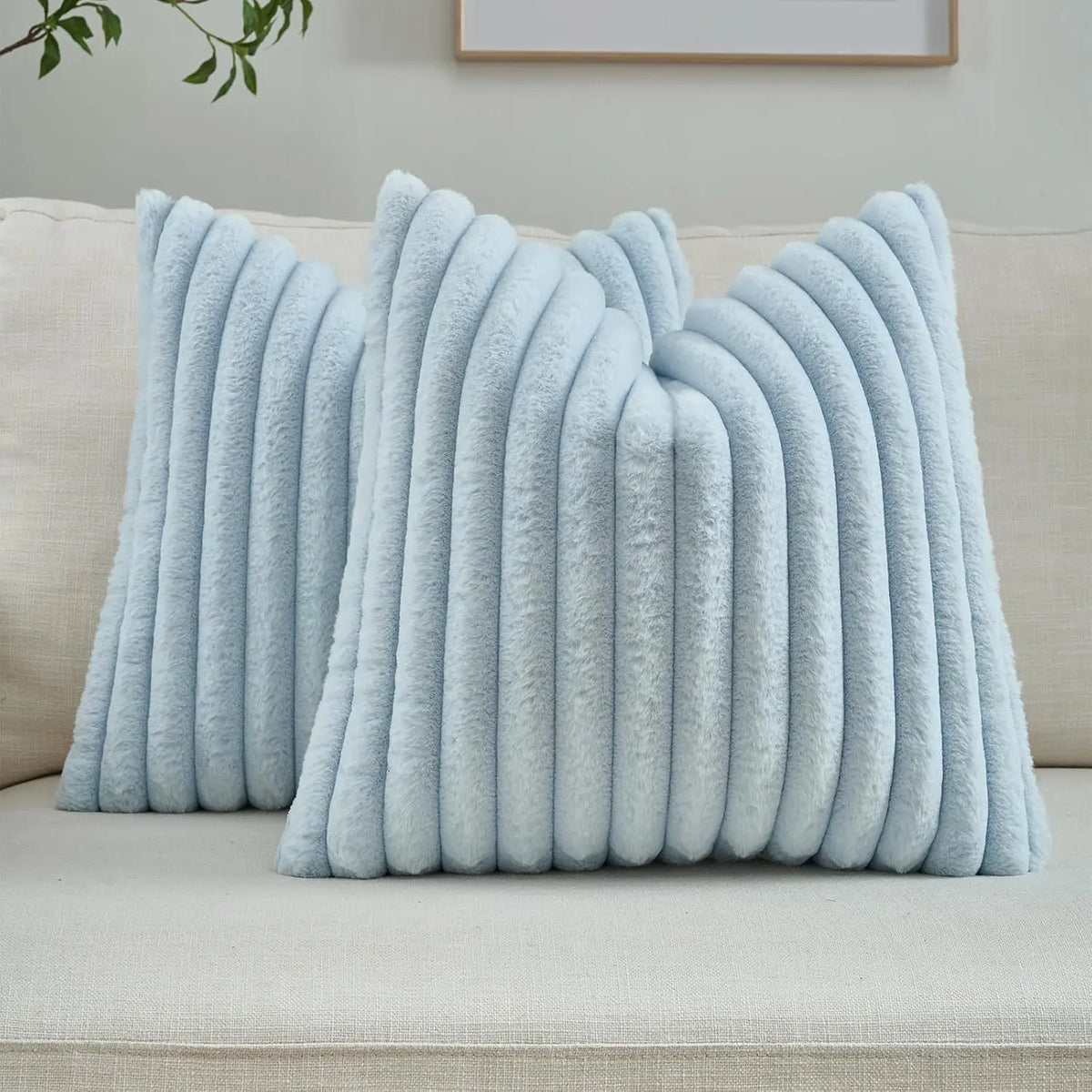 Light blue faux rabbit fur cushion cover with vertical pleats resting on a beige sofa.