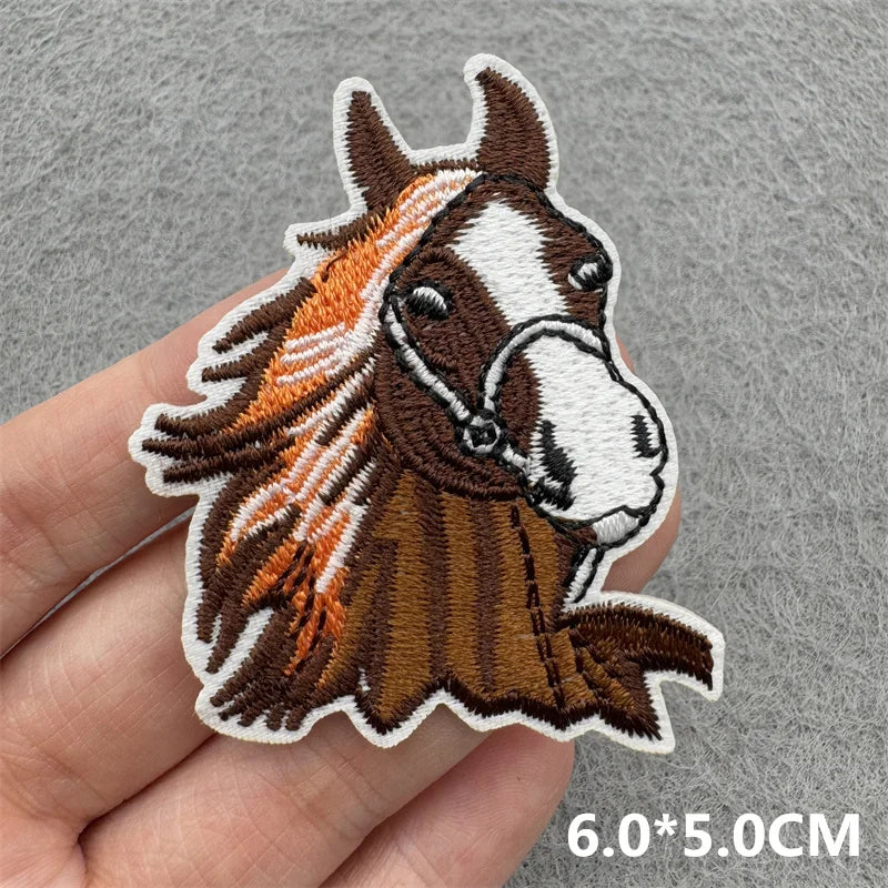 An embroidered patch of a brown and white horse head with a flowing mane on a hand.