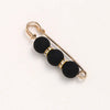 Gold-toned adjustable pearl brooch featuring black spherical beads and small clear stones.