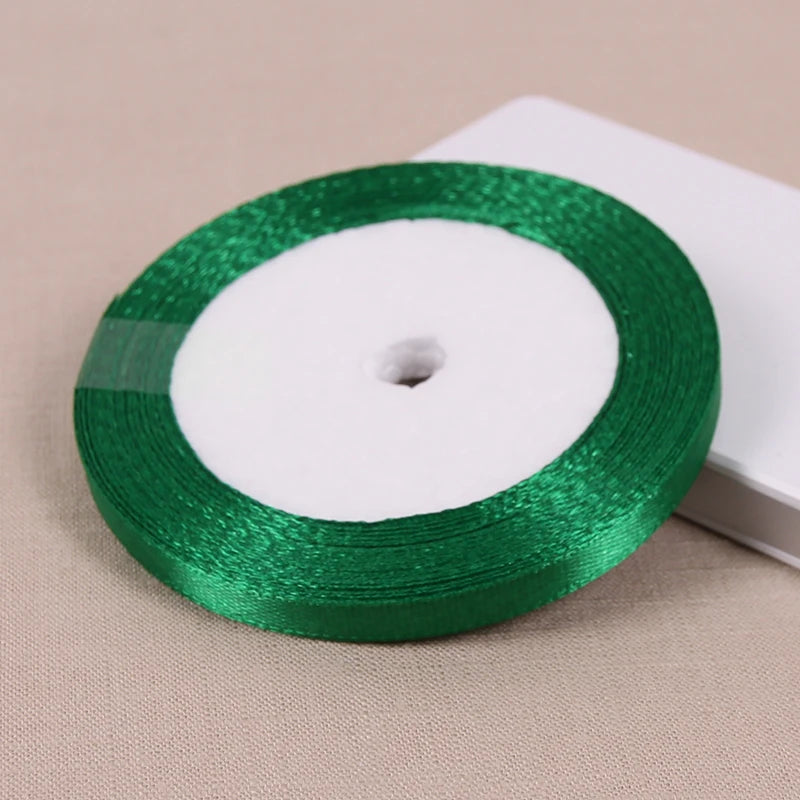 A roll of green satin ribbon with a white center core is shown on a light background.