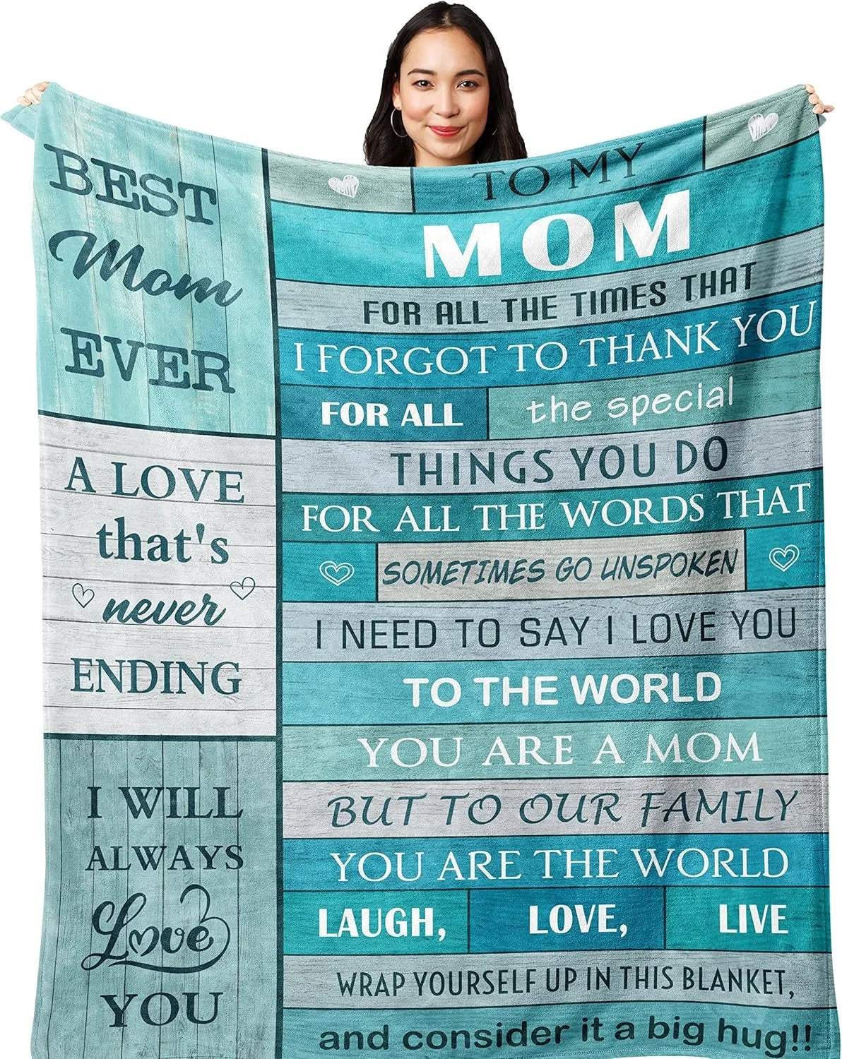A woman smiling while holding a teal and gray printed throw blanket with text dedicated to her mom.