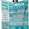 A woman smiling while holding a teal flannel throw blanket with text dedicated to her mom.