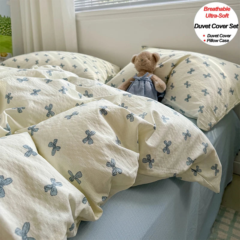 A set of light cream and blue floral patterned duvet covers and pillowcases displayed on a bed.