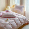 A pink quilt duvet set with striped fabric and decorative bows is displayed on a bed next to a window.