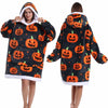 A woman models an oversized patchwork fleece hoodie featuring orange pumpkin designs on a dark background.