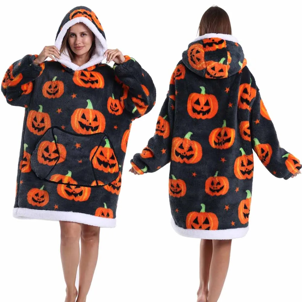 A woman models an oversized patchwork fleece hoodie featuring orange pumpkin designs on a dark background.