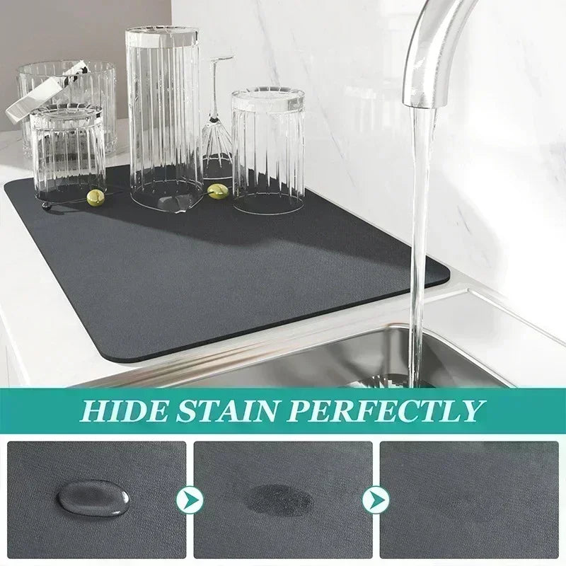 A black non-slip dish drying mat is shown next to a kitchen sink with a faucet, demonstrating its ability to hide stains.