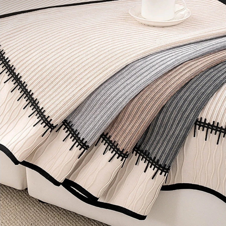 A close-up of a beige and gray striped chenille pleated sofa cover displayed on a white surface.
