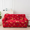 A red festive sofa cover featuring reindeer and Christmas patterns displayed on a white wooden bench.
