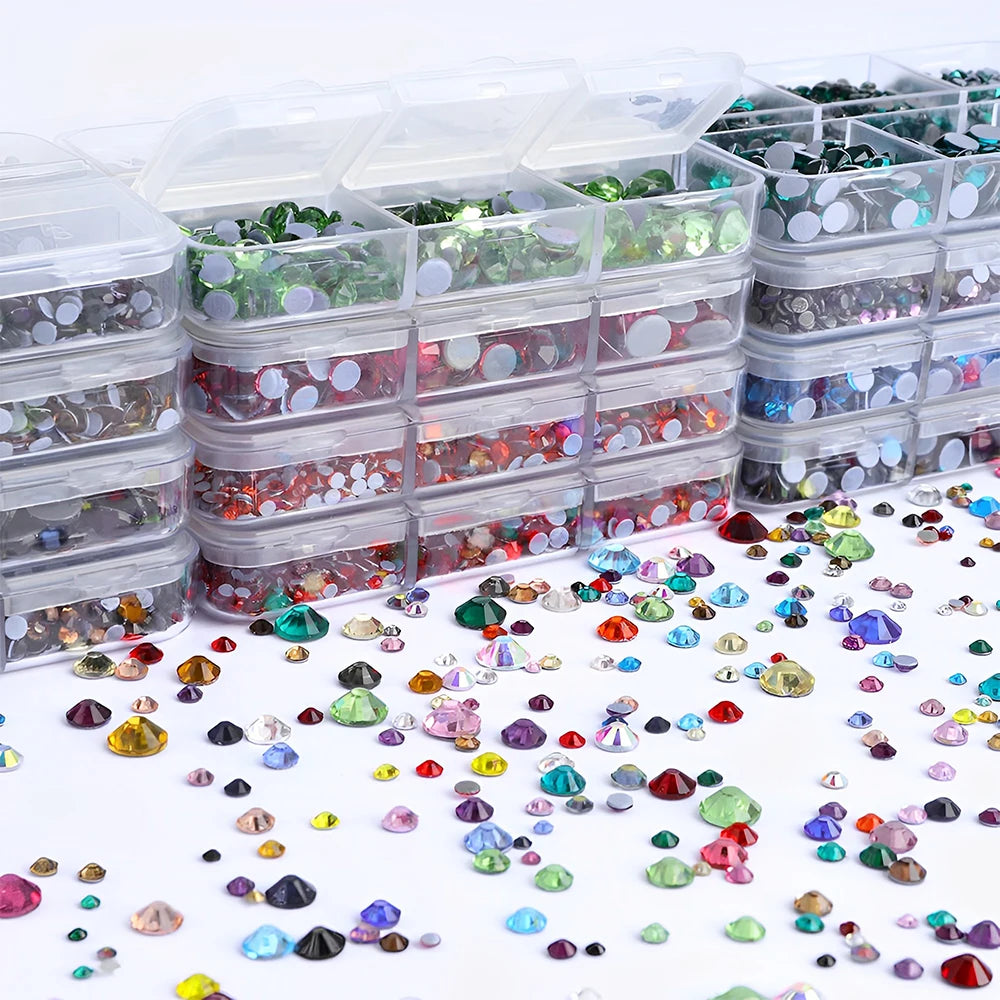 A collection of mixed size hotfix glass rhinestones in various colors and shapes displayed in clear plastic containers.