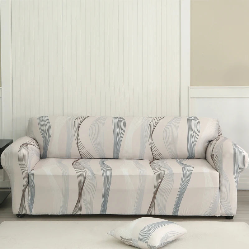 A light beige stretch floral elastic sofa cover displayed on a white floor against a paneled wall.