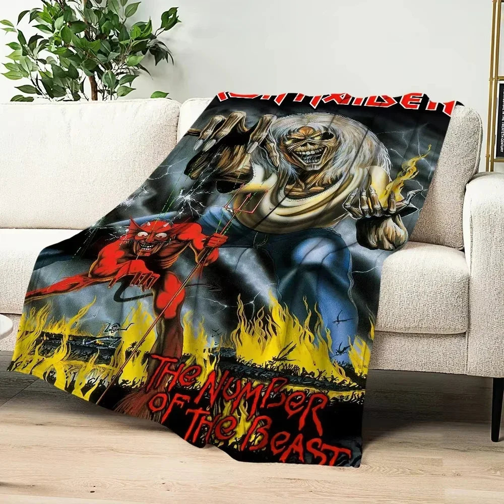 A dark graphic blanket featuring a skeletal devil with flames and text on a couch.