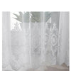 White embroidered floral tulle window curtain hanging in a sheer drape.