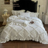 A white ruffled duvet cover set with pillowcases and a pillow core displayed on a bed.
