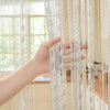 A hand is touching a sheer white beaded string curtain hanging vertically, showing the delicate strands and texture.