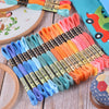 A collection of 12 pack rainbow gradient embroidery floss threads in various shades laid out on a wooden surface.