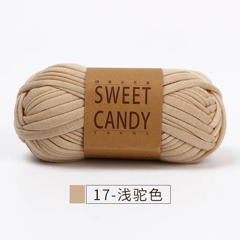 A skein of beige hand-dyed fabric strip yarn labeled Sweet Candy Yarns.