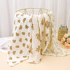 Cream and gold patterned printable cotton crib sheets draped over a gold hanger.