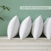 White feather throw pillow inserts displayed on a light gray mantelpiece with a soft green background.