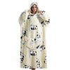 A woman wearing a cream-colored sherpa fleece oversized blanket hoodie with black panda patterns.