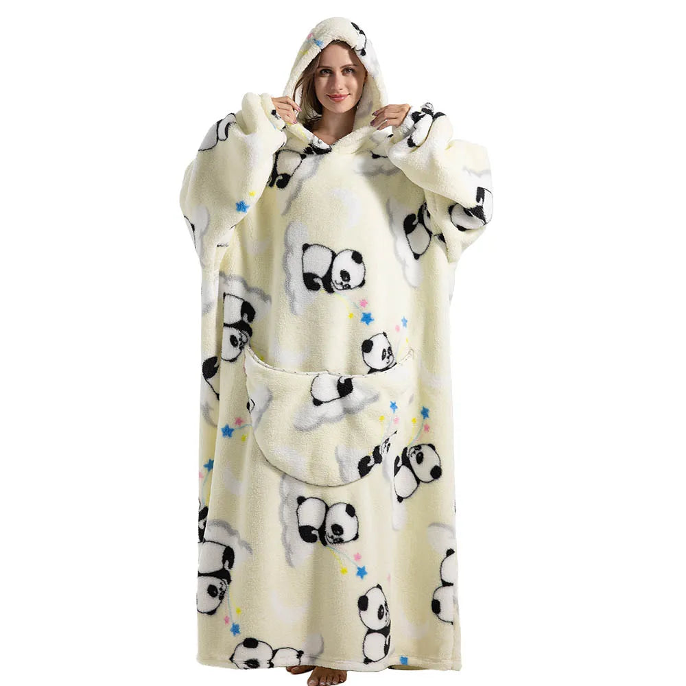A woman wearing a cream-colored sherpa fleece oversized blanket hoodie with black panda patterns.