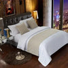 A luxurious bedroom featuring a bed with white linens and decorative pillows, illuminated by warm lighting.