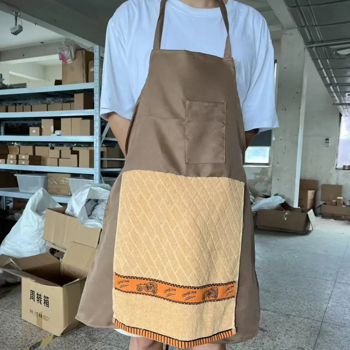 A brown apron with a beige pocket featuring an orange embroidered design and a patterned fabric.