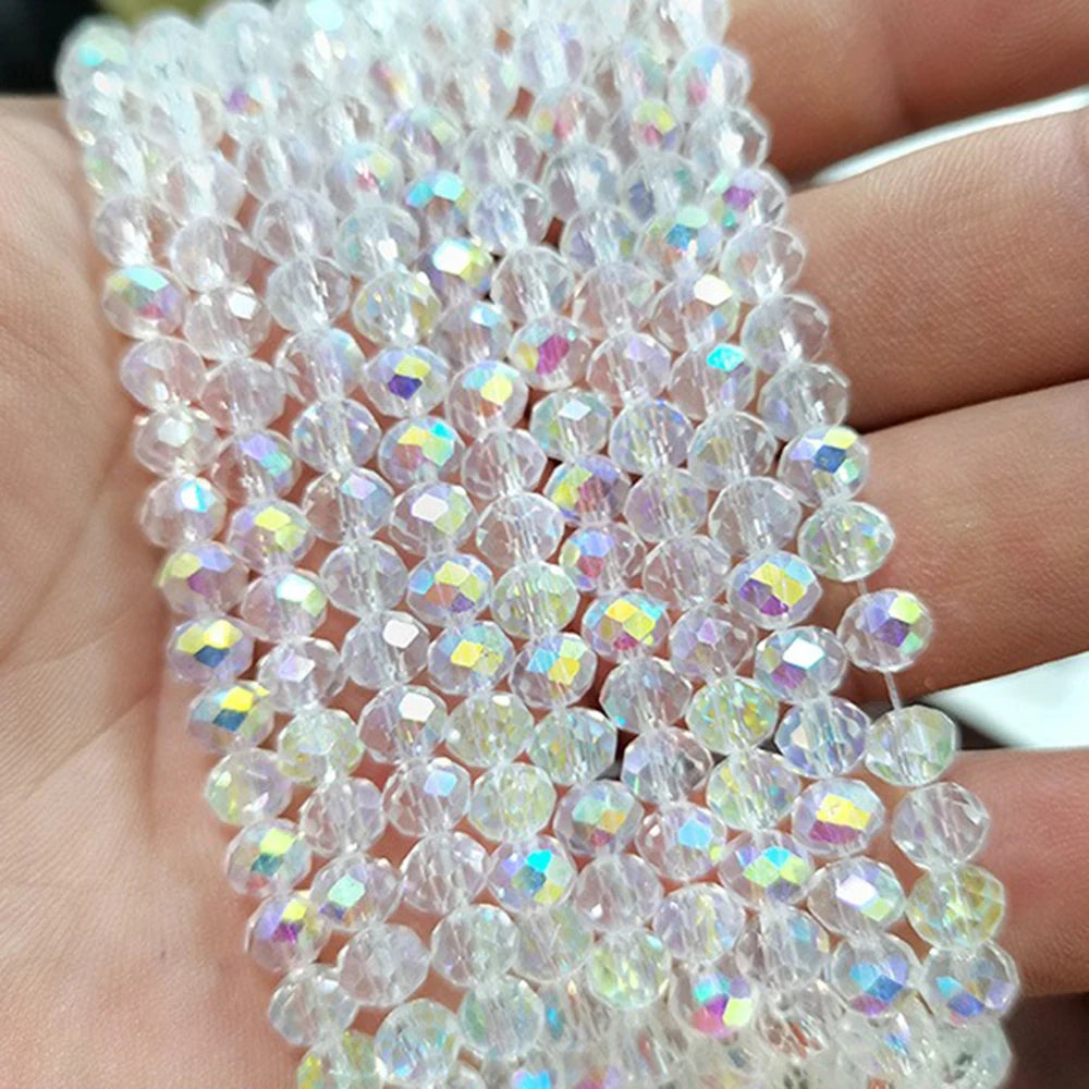 A close-up of clear faceted rondelle glass beads strung together on a hand.