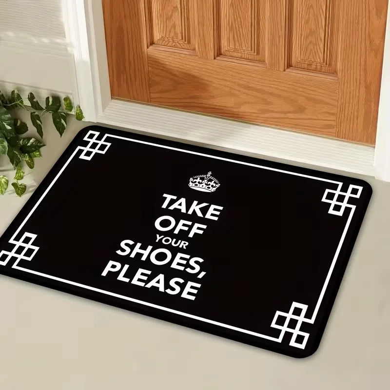 Black doormat with white text that reads Take Off Your Shoes Please and features a crown design