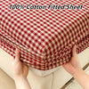 A close-up of a red and cream checkered cotton fitted sheet being held up to show its texture.