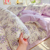 A close-up of a lavender print duvet cover set and pillows with purple floral patterns.