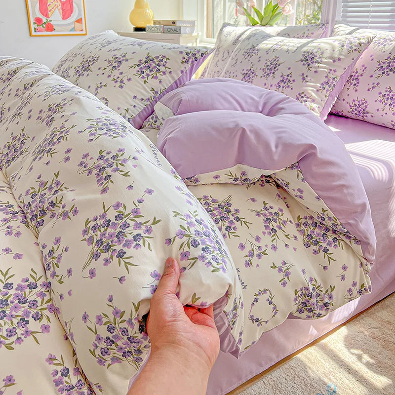 A close-up of a lavender print duvet cover set and pillows with purple floral patterns.