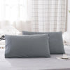 A set of two soft gray polyester pillow covers resting on a light gray bed sheet.