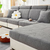 A gray leaf jacquard stretch sofa cover displayed on a modern sectional sofa with white decorative pillows.