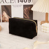Black textured cosmetic storage pouch with a gold zipper displayed on a white surface.
