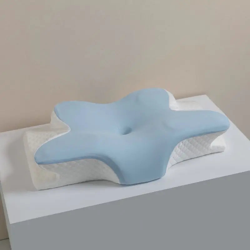 Light blue ergonomic memory foam cervical pillow resting on a white surface.