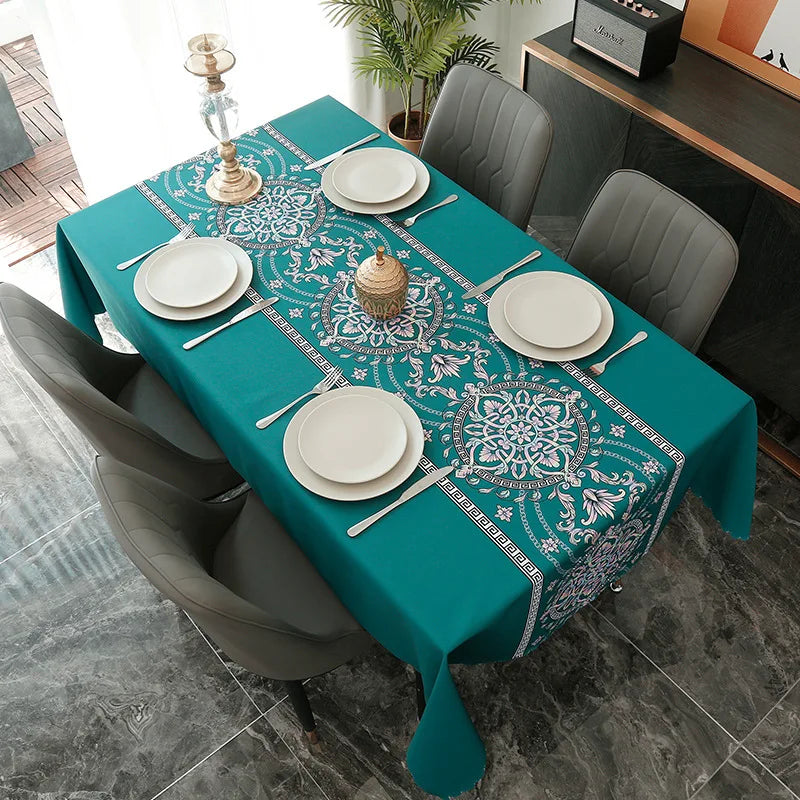 A teal rectangular tablecloth set for dining featuring a white and blue floral pattern with place settings.