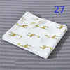 White cotton muslin swaddle blanket with yellow animal print designs folded on a gray background.