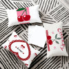 A set of pink and red cherry themed cushion covers featuring cute anime cartoon designs on a gray striped fabric.