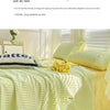 A light green Korean style seersucker summer quilt set with white stripes displayed on a bed.