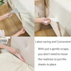 A hand uses a tool to gently scrape bed sheets onto a mattress without moving it.