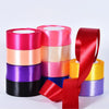 Rolls of satin ribbon in various colors including pink, peach, purple, and black for crafts and gift wrapping