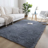 A fluffy gray rug in a modern Nordic style placed on a light wood floor next to a white sofa and potted plant.