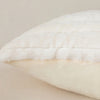 A close-up view of a white plush decorative pillowcase with subtle stripes and a visible seam.