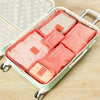 A light green travel organizer storage set with six pink and beige pouches inside.